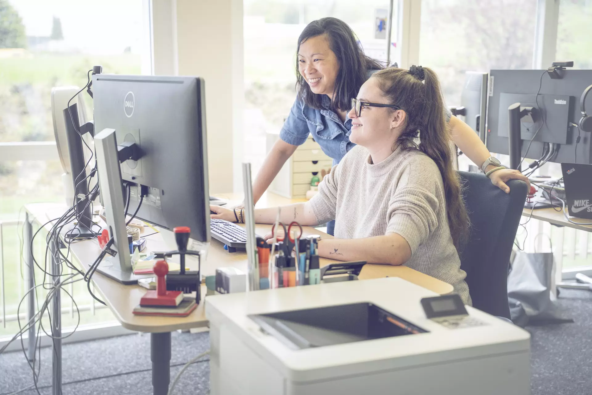 apprentie employée de commerce et sa formatrice devant un ordinateur