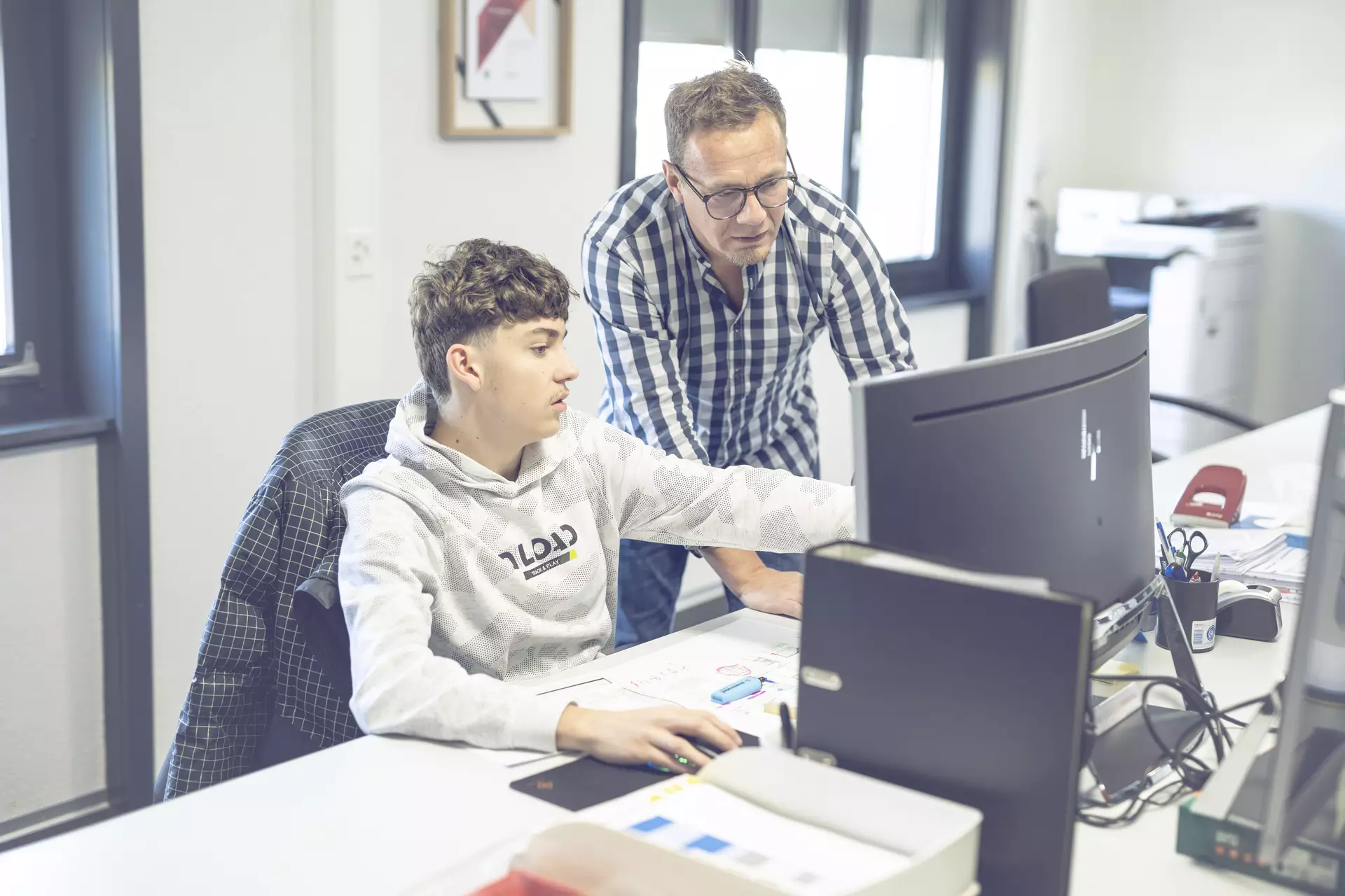 apprenti dessinateur montrant quelque chose à son formateur sur l'ordinateur