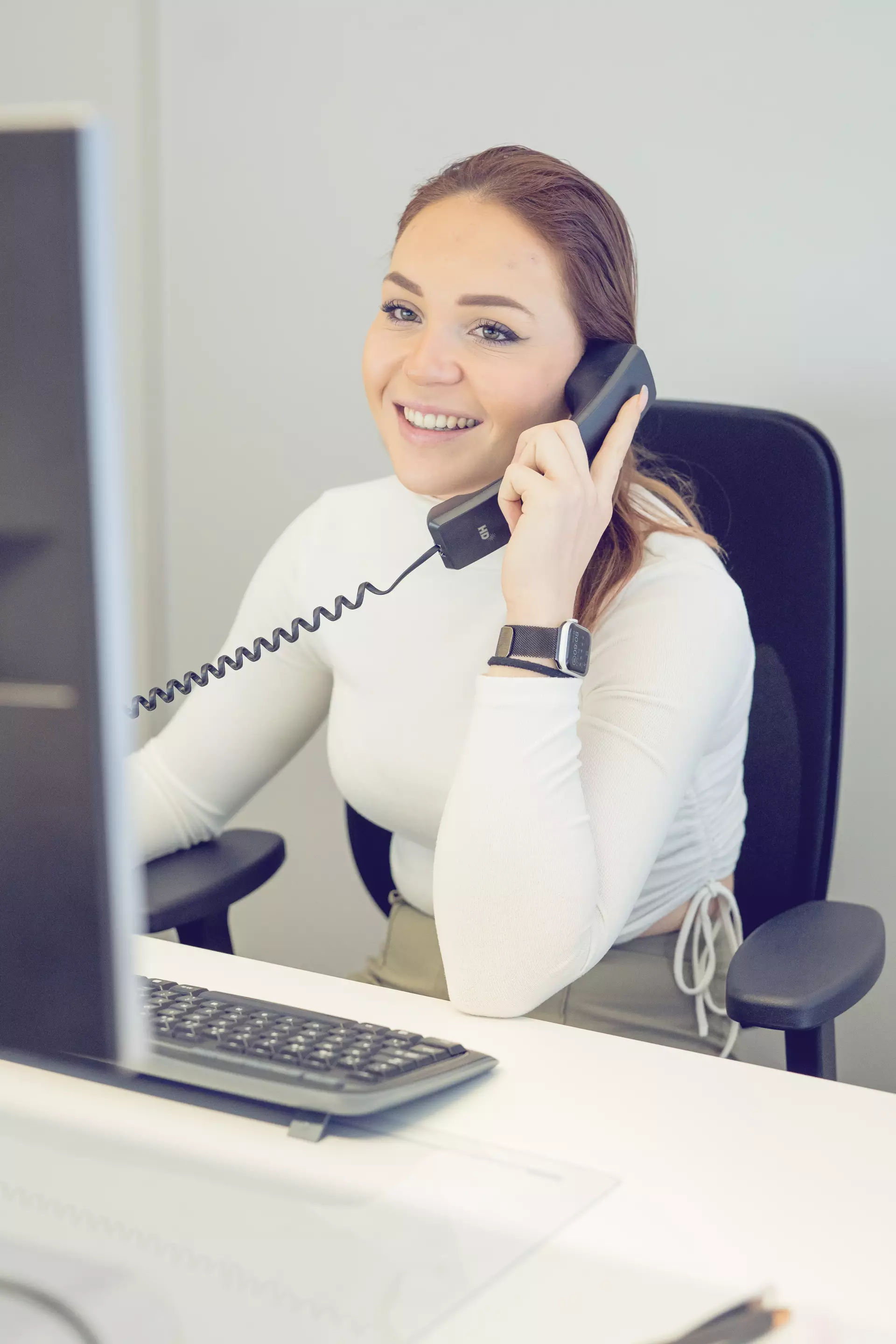 Apprentie employée de commerce au téléphone devant son ordinateur