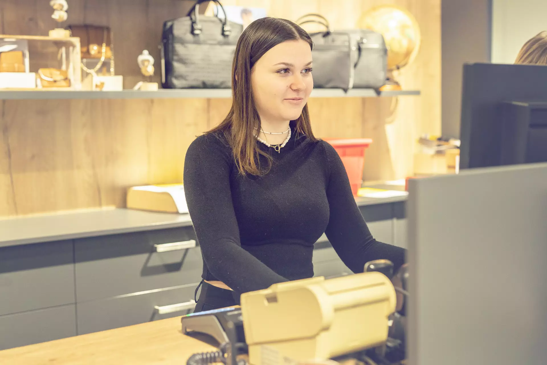 apprentie employée de commerce se tenant debout regardant son ordinateur