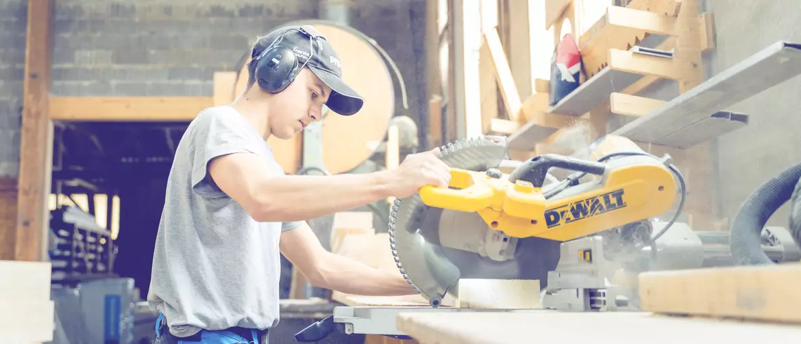 Apprenti charpentier en train de découper des bouts de bois