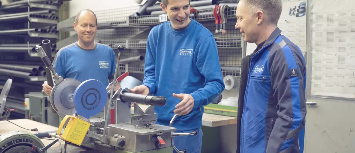 Apprenti chauffage sanitaire et ses formateurs en train de discuter autour de son poste de travail