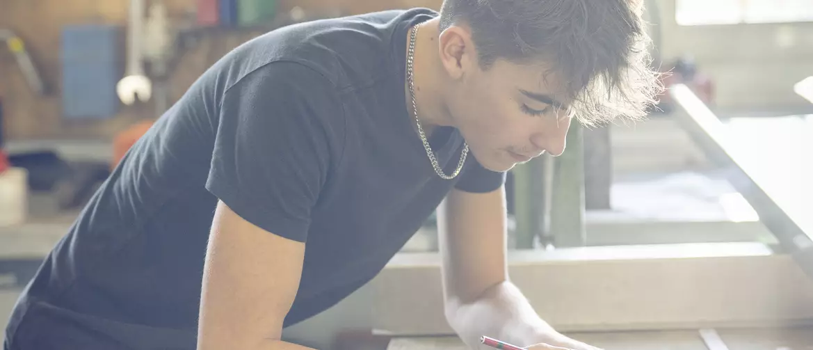 apprenti ferblantier découpant une pièce sur une place de travail