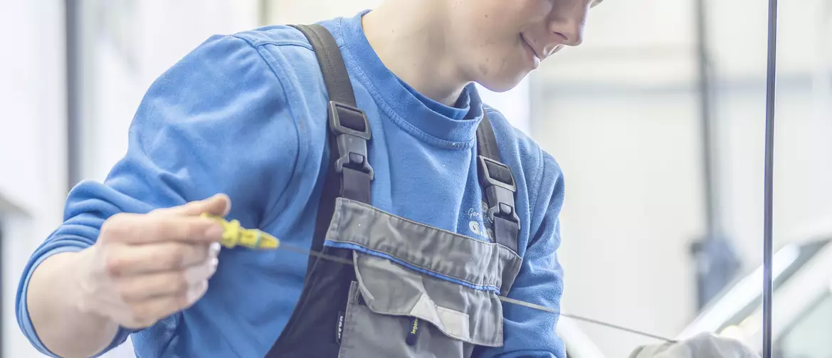 Apprenti mécanicien prenant la mesure de l'huile sous un capot de voiture
